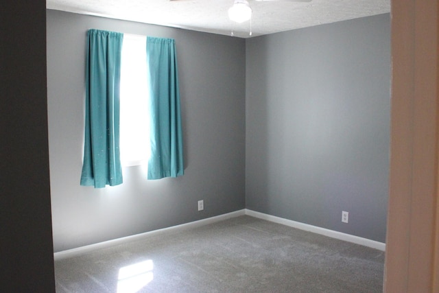 carpeted empty room featuring ceiling fan and baseboards