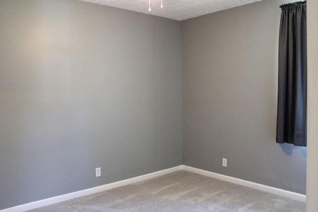 carpeted spare room with a textured ceiling and baseboards