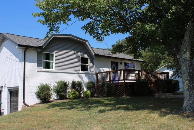 rear view of property with a garage, a wooden deck, and a yard