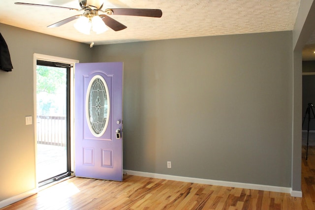 entryway with a textured ceiling, light wood-type flooring, a ceiling fan, and baseboards