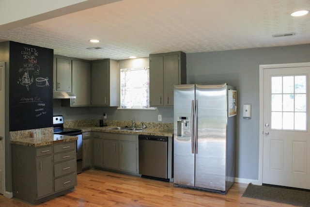 kitchen featuring light stone countertops, visible vents, appliances with stainless steel finishes, and a sink