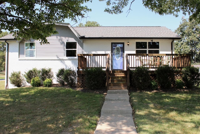 ranch-style house featuring a deck, brick siding, a front yard, and a shingled roof