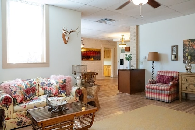 living room with a drop ceiling, hardwood / wood-style floors, and ceiling fan