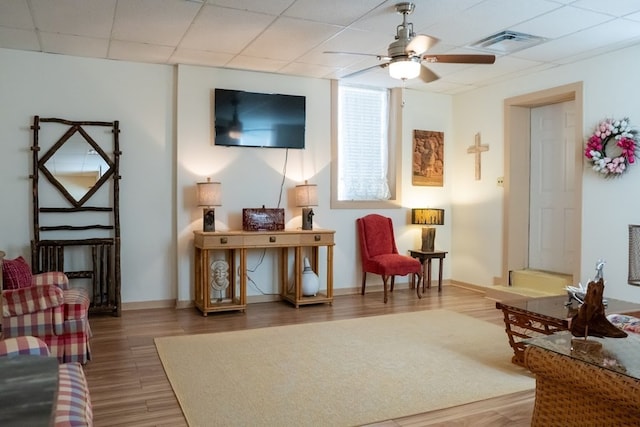 living area featuring ceiling fan, hardwood / wood-style flooring, and a drop ceiling