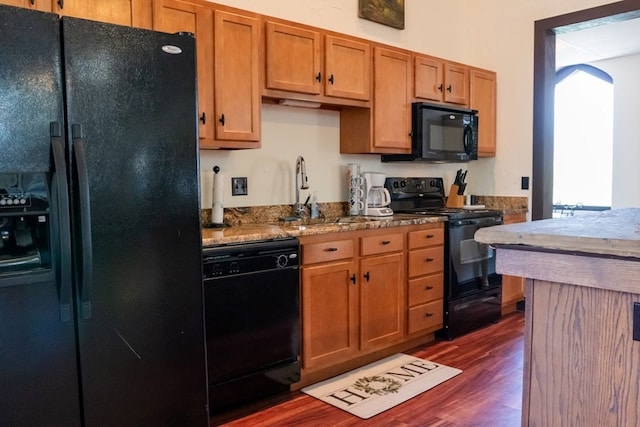 kitchen featuring dark wood-type flooring, black appliances, and sink