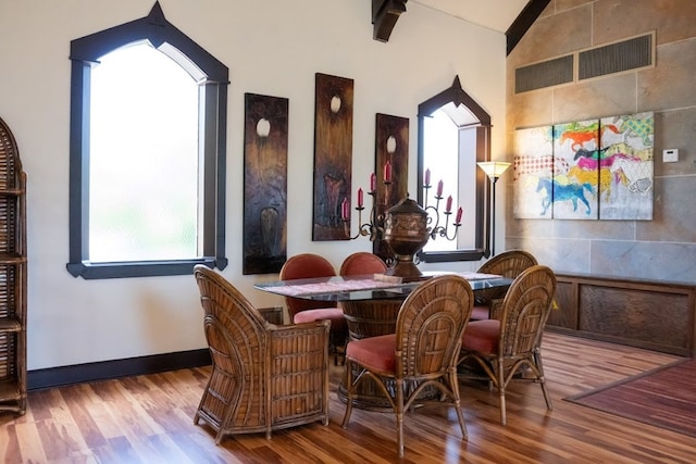 dining area featuring hardwood / wood-style flooring and vaulted ceiling