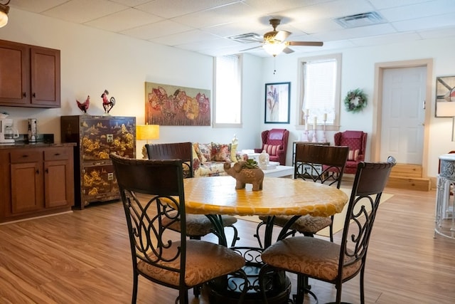 dining area with light wood-type flooring and ceiling fan