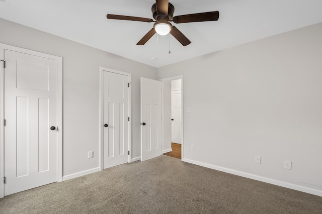 unfurnished bedroom with light carpet, ceiling fan, and two closets