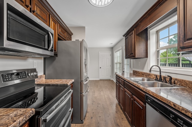 kitchen with dark brown cabinetry, sink, light hardwood / wood-style flooring, and stainless steel appliances