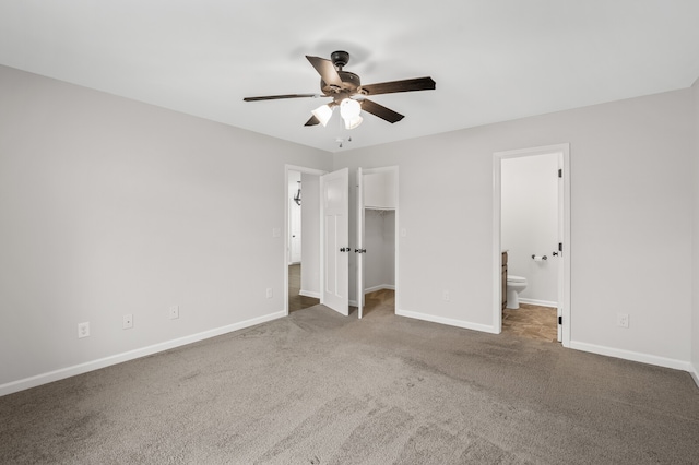 unfurnished bedroom with ceiling fan, ensuite bathroom, a walk in closet, carpet, and a closet