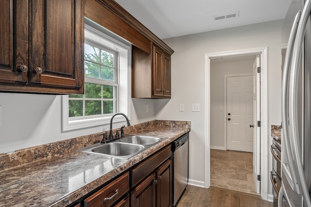 kitchen with sink, hardwood / wood-style flooring, appliances with stainless steel finishes, and dark brown cabinetry