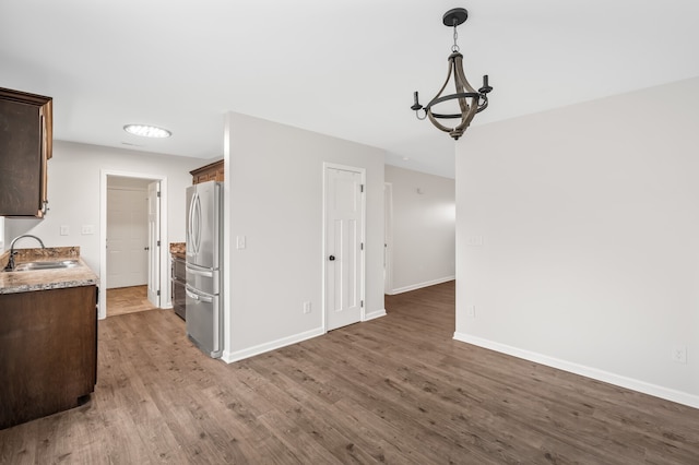 kitchen with sink, hardwood / wood-style flooring, stainless steel fridge, and decorative light fixtures