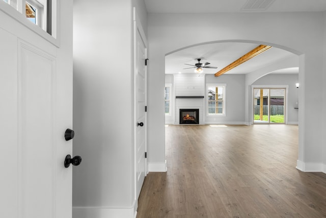 interior space featuring hardwood / wood-style floors, ceiling fan, beamed ceiling, and a large fireplace