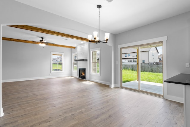 unfurnished living room featuring beam ceiling, wood-type flooring, a chandelier, and a fireplace