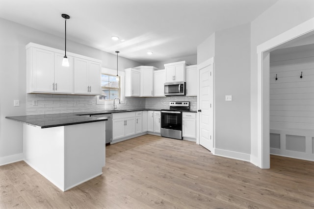 kitchen featuring white cabinetry, hanging light fixtures, kitchen peninsula, stainless steel appliances, and decorative backsplash