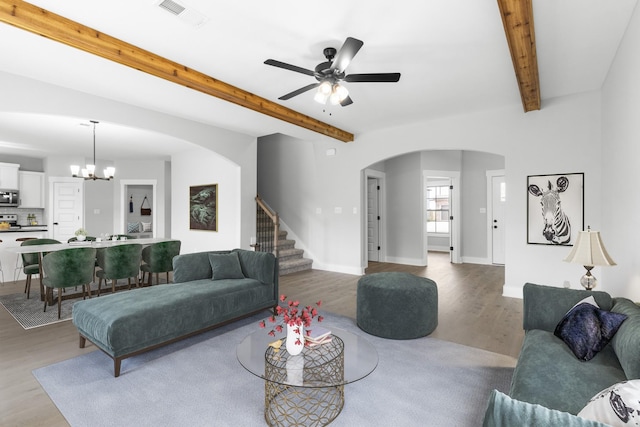 living room with ceiling fan with notable chandelier, wood-type flooring, and beamed ceiling