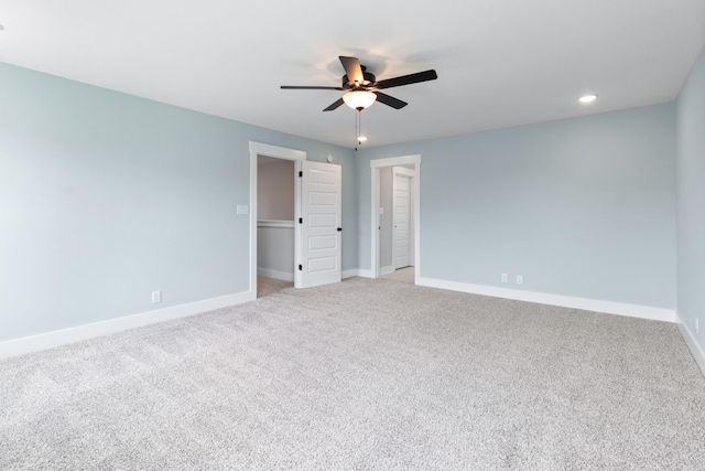 unfurnished bedroom with light carpet, a spacious closet, a closet, and ceiling fan