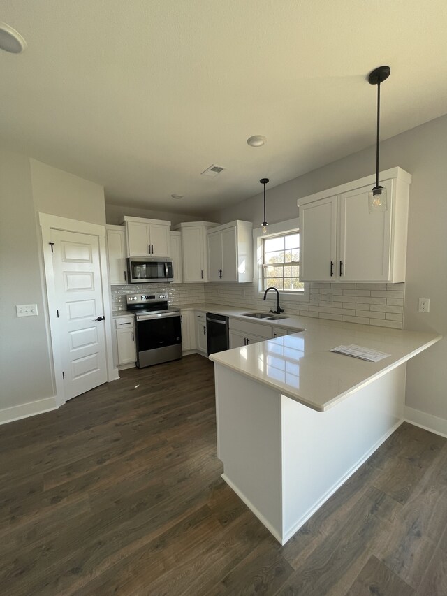 kitchen featuring sink, appliances with stainless steel finishes, white cabinetry, decorative light fixtures, and kitchen peninsula