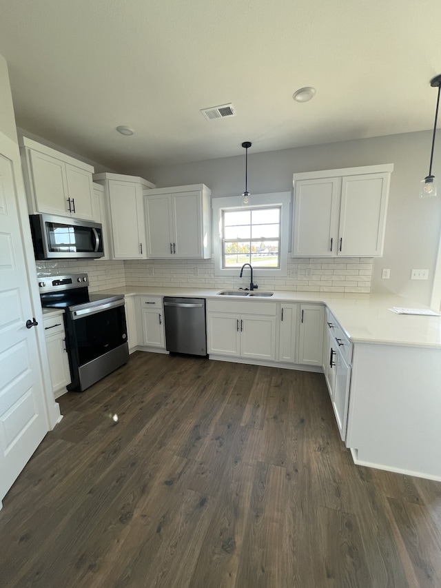 kitchen featuring stainless steel appliances, decorative light fixtures, and white cabinets