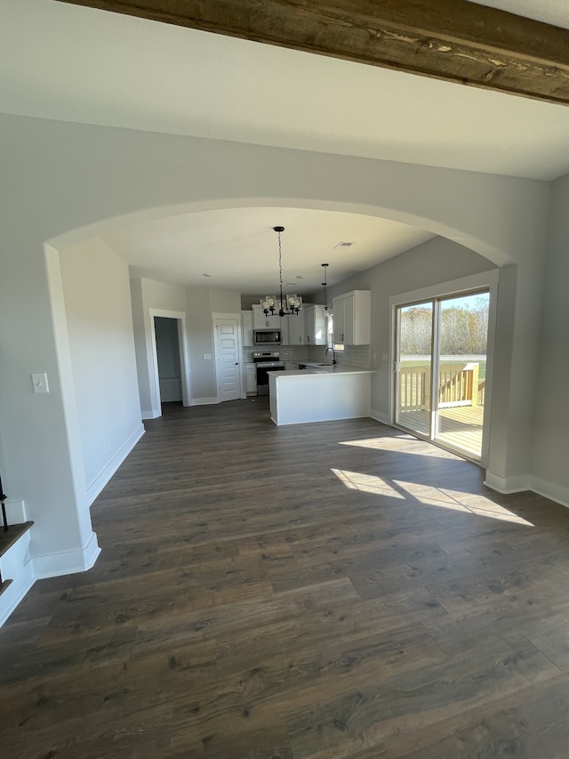 unfurnished living room featuring dark hardwood / wood-style floors, sink, and an inviting chandelier