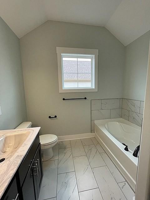 bathroom with a tub to relax in, lofted ceiling, toilet, and vanity