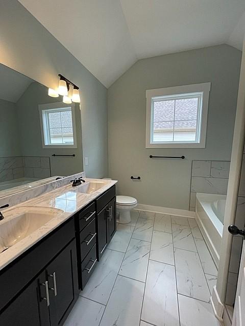 bathroom with a healthy amount of sunlight, lofted ceiling, toilet, and vanity