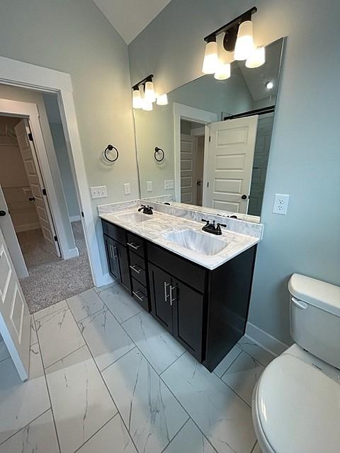 bathroom with lofted ceiling, toilet, and vanity