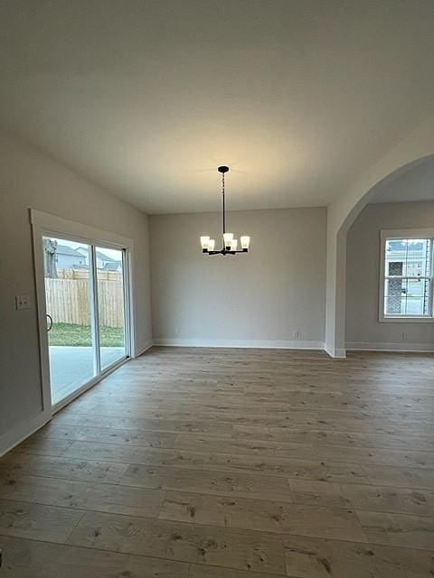 empty room with an inviting chandelier, hardwood / wood-style flooring, and plenty of natural light