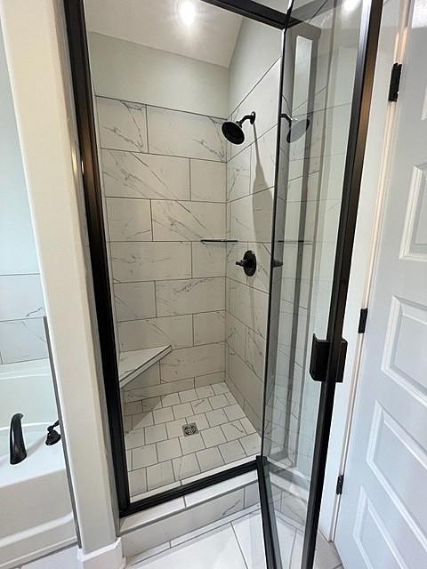 bathroom with tile patterned flooring and tiled shower