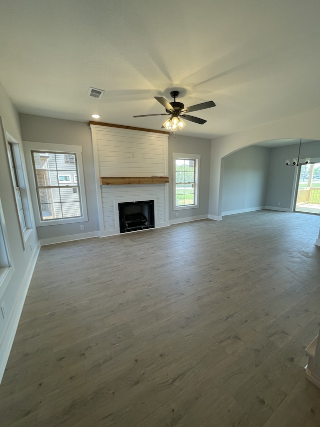 unfurnished living room featuring hardwood / wood-style flooring, ceiling fan, and a fireplace