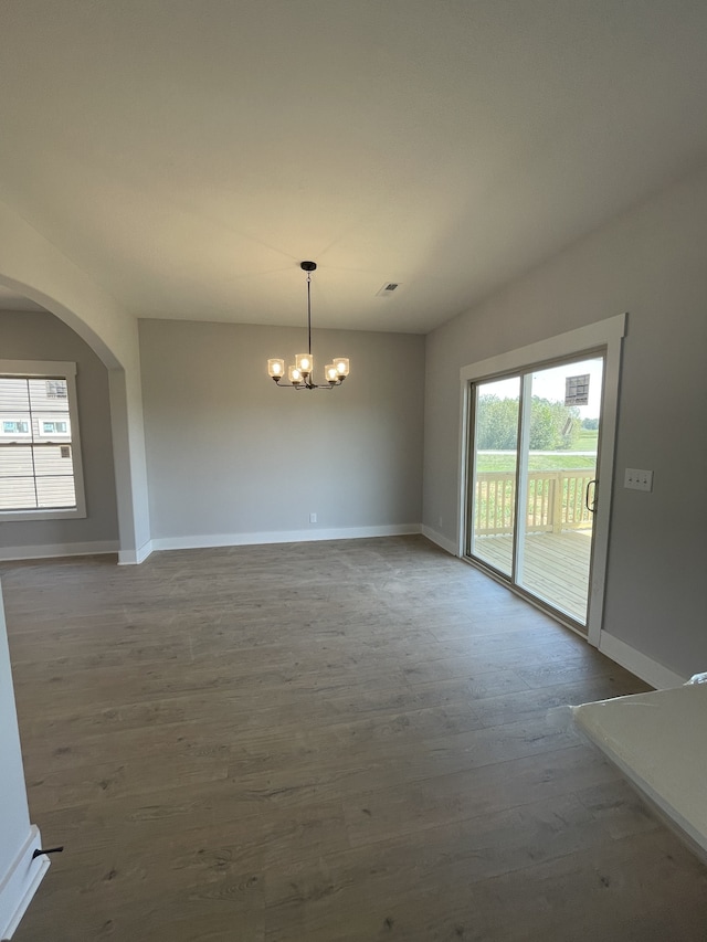 empty room featuring wood-type flooring and a chandelier