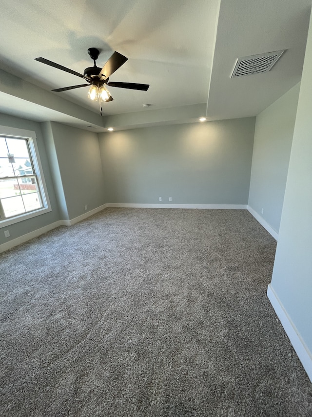 carpeted empty room featuring a tray ceiling and ceiling fan