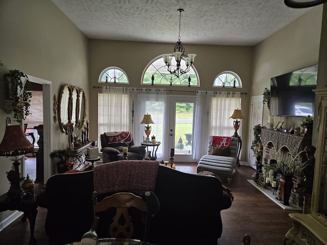 living room featuring a textured ceiling, dark hardwood / wood-style floors, a chandelier, and a towering ceiling