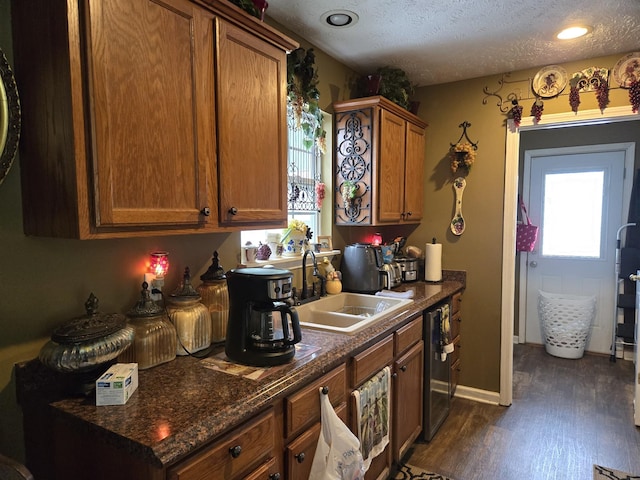 kitchen featuring dark wood-type flooring, sink, a textured ceiling, and dark stone countertops