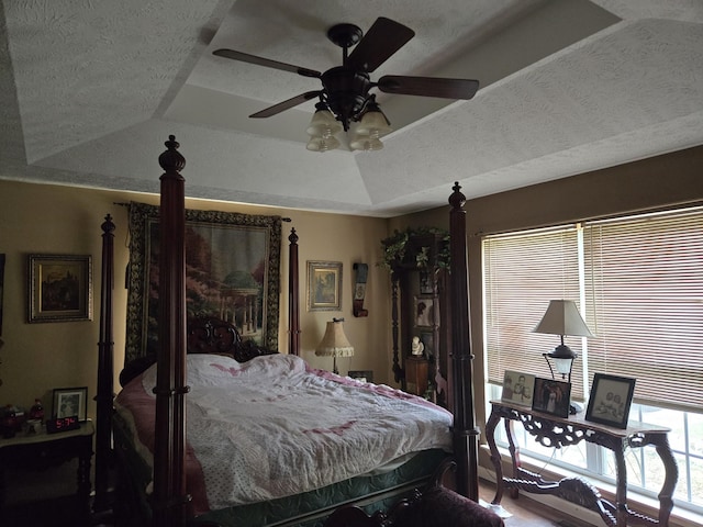 bedroom featuring a raised ceiling, a textured ceiling, and ceiling fan