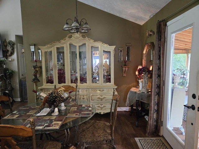 dining room with lofted ceiling, a notable chandelier, dark wood-type flooring, and a textured ceiling