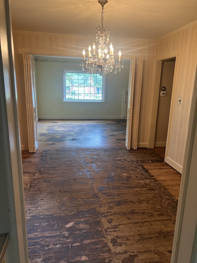 unfurnished dining area with dark hardwood / wood-style flooring, ornamental molding, and an inviting chandelier