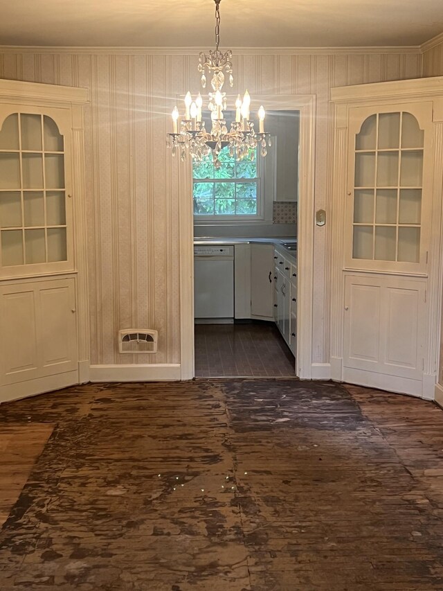 unfurnished dining area with dark hardwood / wood-style floors, ornamental molding, and a chandelier