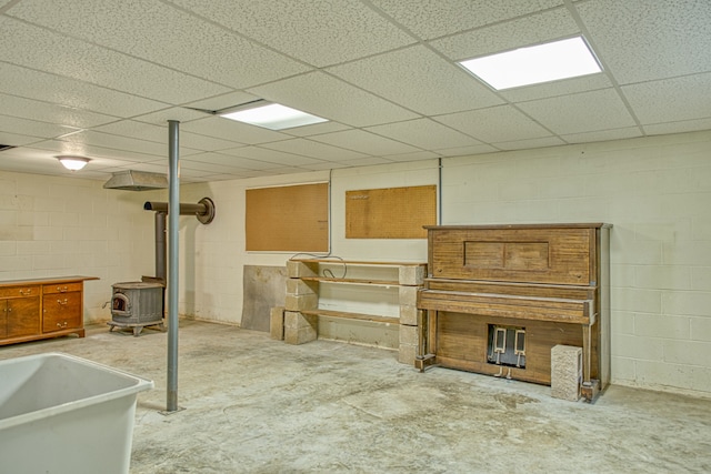 basement with a paneled ceiling and a wood stove