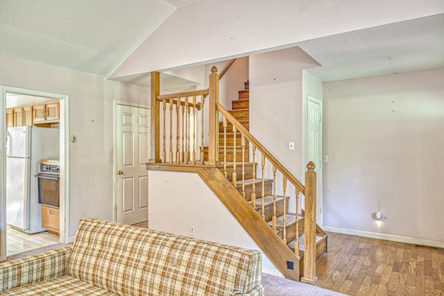 stairs featuring hardwood / wood-style flooring, a textured ceiling, and vaulted ceiling