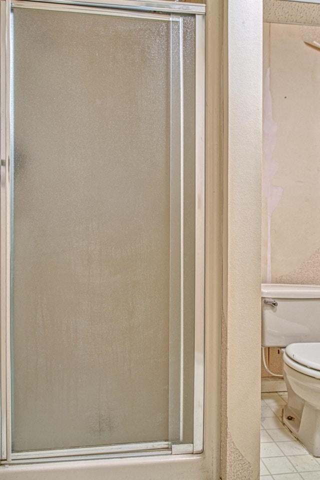 bathroom with toilet, tile patterned floors, and an enclosed shower