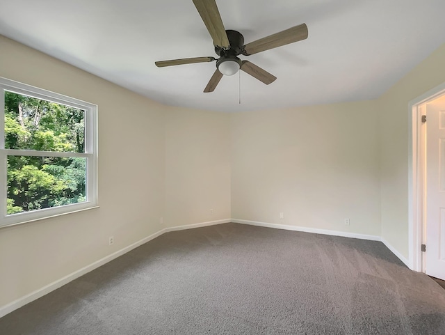 empty room featuring ceiling fan and dark colored carpet