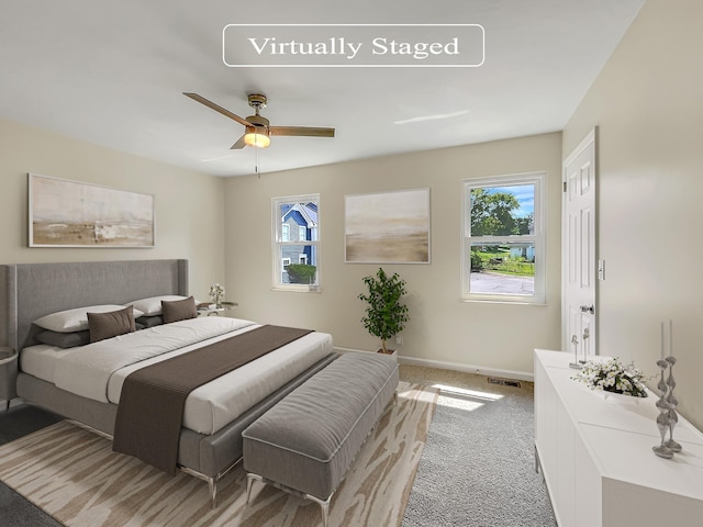 carpeted bedroom featuring multiple windows and ceiling fan