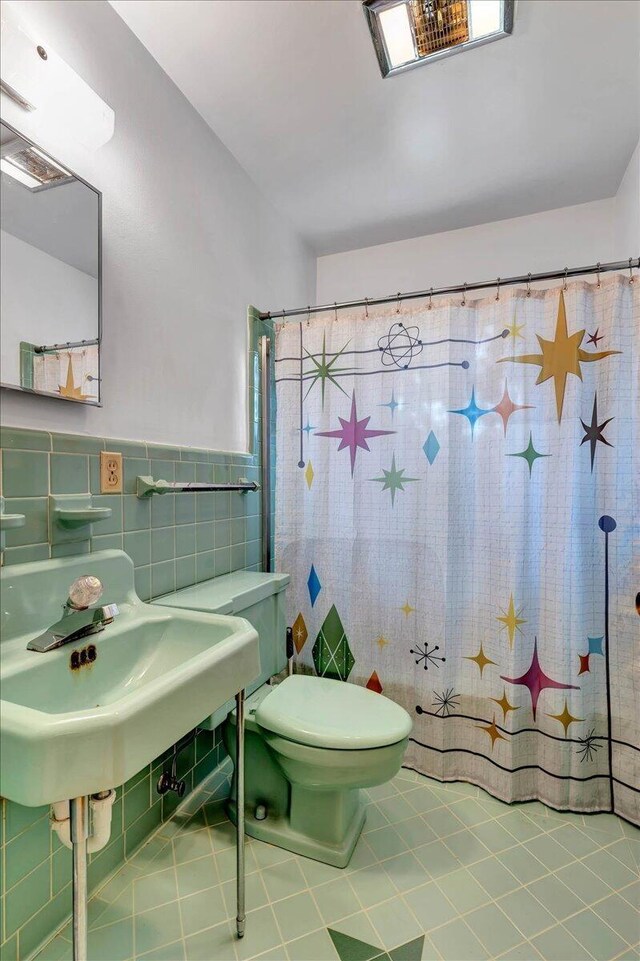 bathroom featuring tile patterned flooring, tasteful backsplash, toilet, tile walls, and sink