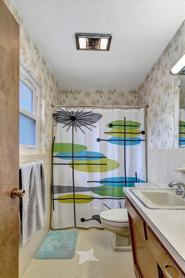 bathroom with backsplash, toilet, vanity, tile walls, and tile patterned floors