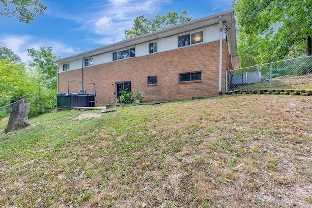 rear view of property with a lawn and a hot tub