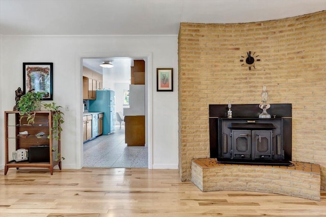 living room with crown molding, light hardwood / wood-style floors, and a wood stove