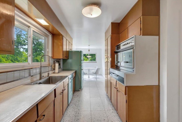 kitchen with dishwashing machine, sink, stainless steel fridge, and a healthy amount of sunlight