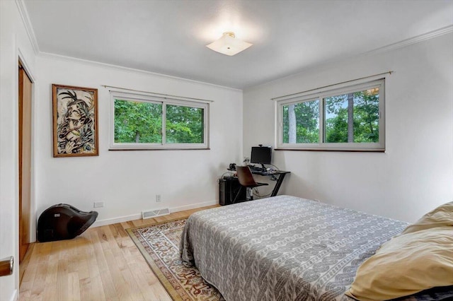 bedroom featuring crown molding, a closet, light hardwood / wood-style floors, and multiple windows