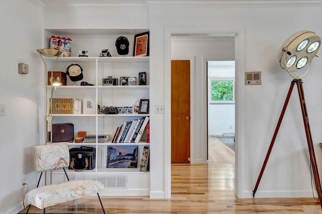 living area with light hardwood / wood-style flooring and crown molding